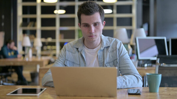 The Young Male Designer using Laptop in Modern Office
