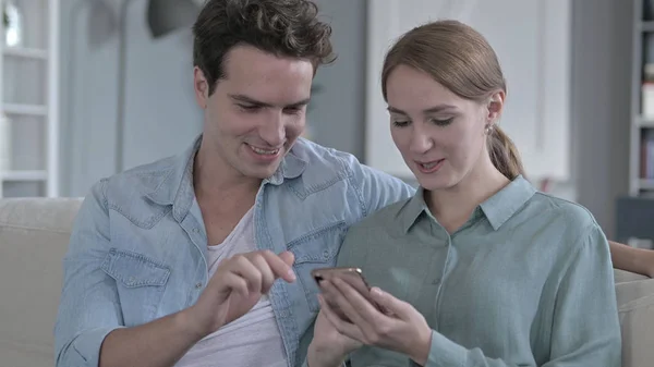 O retrato de casal alegre sentado juntos e usando Smartphone — Fotografia de Stock