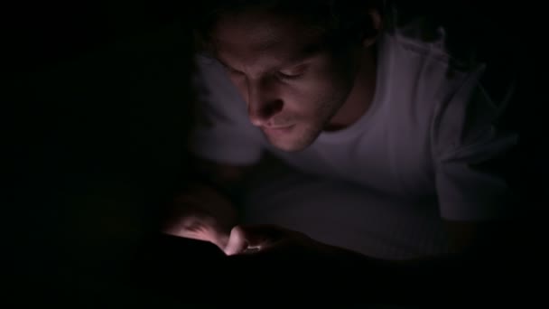 Hombre joven enfocado usando Smartphone en la cama por la noche — Vídeo de stock