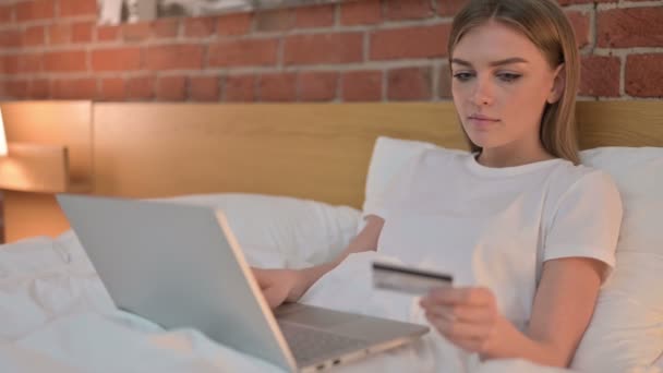 Mujer joven haciendo el pago en línea en el ordenador portátil en la cama — Vídeo de stock