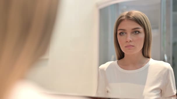 Вид ззаду серйозна молода жінка дивиться у дзеркало — стокове відео
