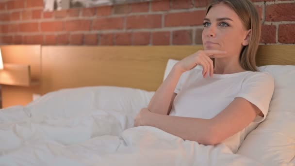 Gondolkodó fiatal nő gondolkodik valami az ágyban — Stock videók