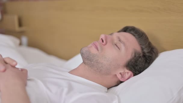 Müder junger Mann versucht, im Bett zu schlafen — Stockvideo