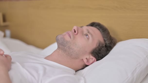Окаменелый молодой человек, размышляющий об идее в постели — стоковое видео