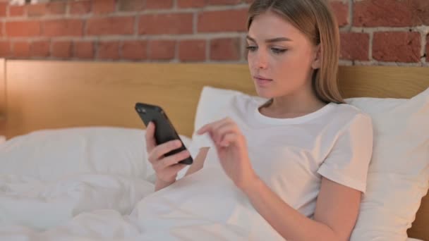 Jovem mulher com falha no smartphone na cama — Vídeo de Stock