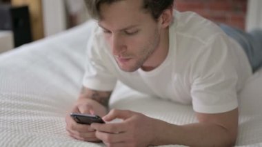 Genç adam yatakta Smartphone 'da şok oldu.