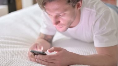 Yataktaki Akıllı Telefondan Hırslı Genç Adam Kayıyor