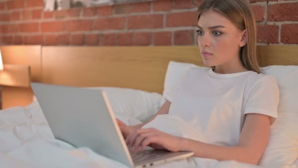 Zdenerwowany młoda kobieta reaguje na utratę na laptopie w łóżku — Wideo stockowe
