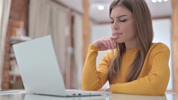 Schöne junge Frau denkt und arbeitet am Laptop — Stockvideo