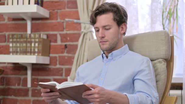 Joven enfocado leyendo un libro en la oficina — Vídeos de Stock