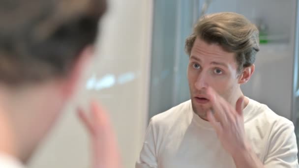 Achteraanzicht van de jonge man bevestiging gezicht in spiegel — Stockvideo