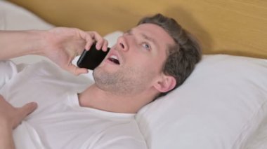 Yatakta Akıllı Telefonla Konuşan Genç Adamın Portresi