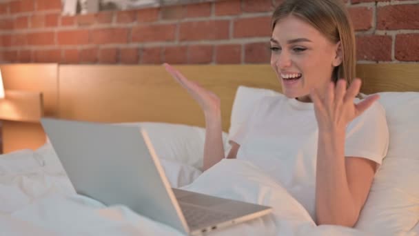 Joven alegre haciendo Video Chat en el ordenador portátil en la cama — Vídeo de stock