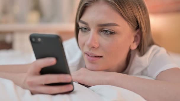 Крупним планом Щаслива молода жінка використовує смартфон у ліжку — стокове відео