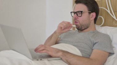 Sakallı genç adam laptopta öksürüyor.