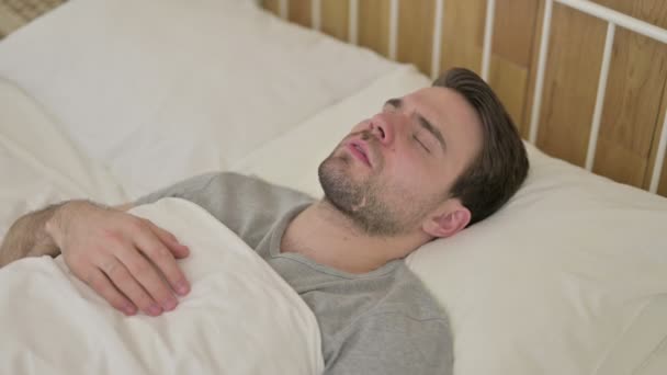 Расстроенный молодой человек с бородой думает в постели — стоковое видео