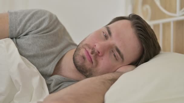 Portrét vousatého mladého muže přemýšlejícího v posteli — Stock video