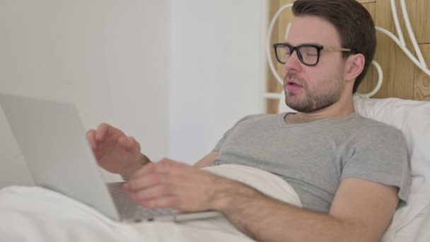 Overstuur baard jongeman krijgen schok op laptop in bed — Stockvideo