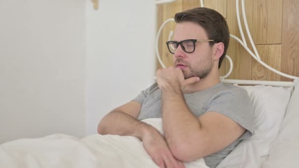 Окаменевший бородатый молодой человек думает об идее в постели — стоковое видео