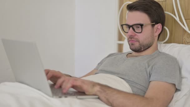 Baard jongeman krijgen verrassing op laptop in bed — Stockvideo