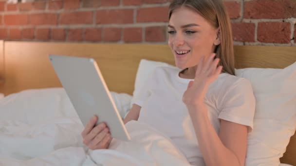 若い女性がベッドでタブレットでビデオチャットを行う — ストック動画