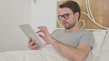 Sakallı genç adam, yatakta Tablet 'e sürpriz yap.