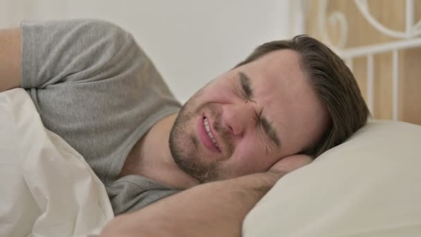 Portret brodatego młodzieńca z bólem głowy w łóżku — Wideo stockowe