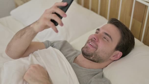 Barba Jovem fazendo Video Chat no Smartphone na cama — Vídeo de Stock