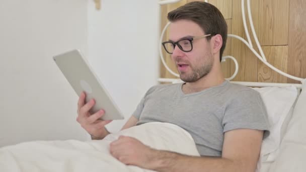 Barba Joven haciendo Video Chat en Tablet en la cama — Vídeos de Stock