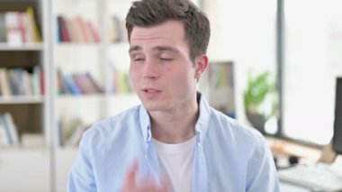 Yorgun genç adam ofiste esniyor.