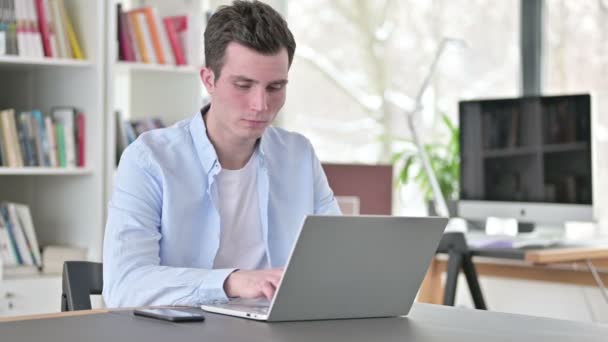 Drukke jonge man die op laptop werkt — Stockvideo