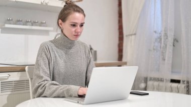 Evde dizüstü bilgisayarda çalışan hırslı genç kadın.