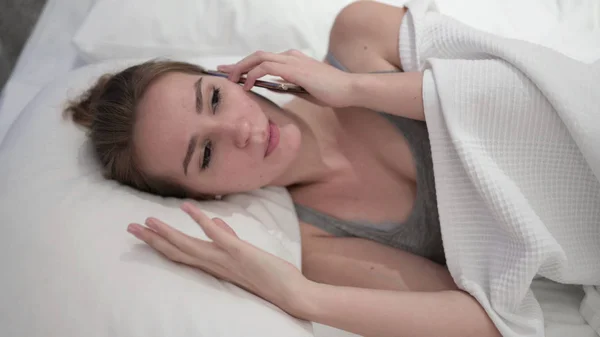 Angry Young Woman talking on Smartphone in Bed — Stock Photo, Image