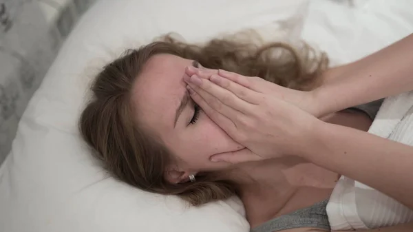 Piangendo giovane donna nascondendo il viso con le mani a letto — Foto Stock