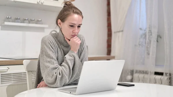Mulher jovem Pensando e trabalhando no laptop em casa — Fotografia de Stock