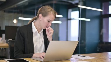 Hasta genç beyaz iş kadını ofiste öksürüyor.