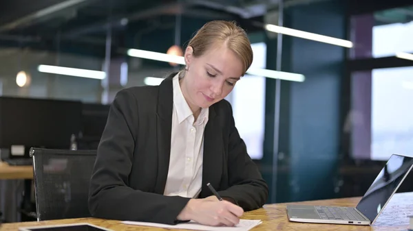 Giovane imprenditrice che cerca di scrivere su documenti in ufficio — Foto Stock
