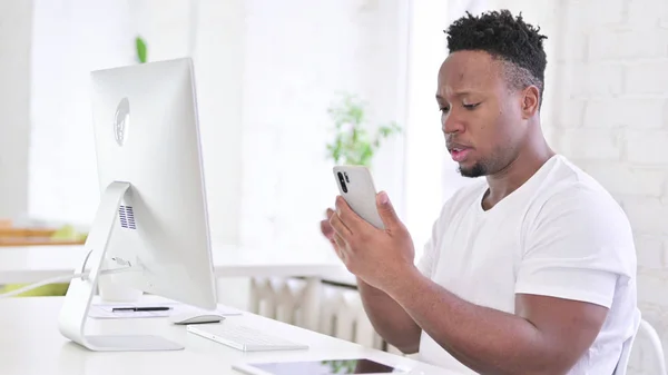 Hombre africano casual enfocado usando Smartphone en la oficina moderna —  Fotos de Stock