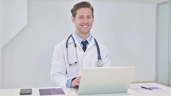 Allegro giovane medico sorridente alla macchina fotografica in clinica — Foto Stock