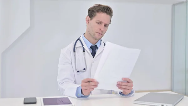 Seriös ung läkare läser medicinsk rapport på kliniken — Stockfoto