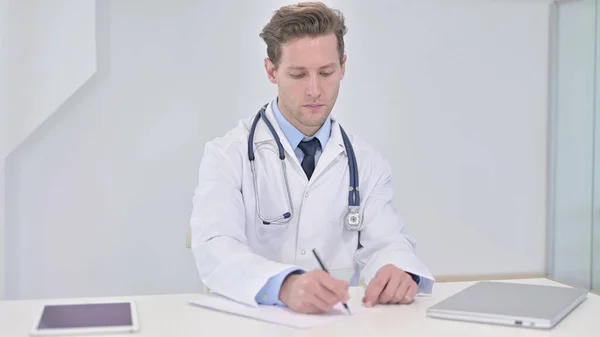Skriva ung doktor gör pappersarbete på kliniken — Stockfoto