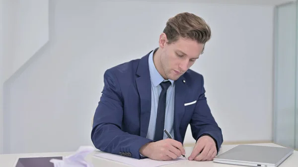 Busy Young Businessman Writing Documents in Office
