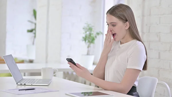 Mujer joven sorprendida por el éxito en el teléfono inteligente — Foto de Stock