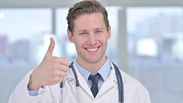 Portrét mladého mužského doktora ukazující palce v kanceláři — Stock fotografie