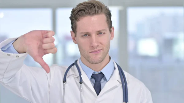 Porträtt av ung manlig läkare visar tummen ner i Office — Stockfoto