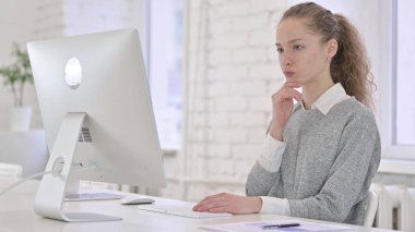 Düşünceli Latin Kadın Masaüstü Bilgisayarı üzerinde Düşünüyor ve Çalışıyor