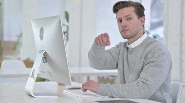 Neşeli genç adam kamerayı işaret ediyor.