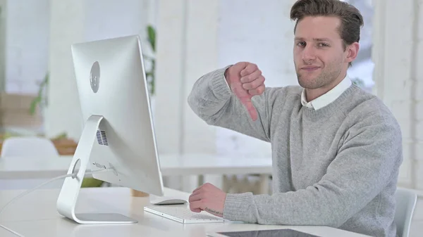 Young Man working on Desktop and doing Thumbs Down — Stock Photo, Image