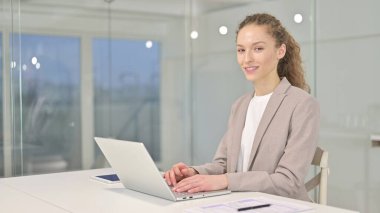 Güzel genç iş kadını Kameraya bakıyor ve gülümsüyor