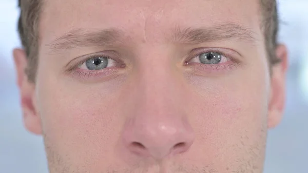 Close-up van knipperende ogen van jonge man op zoek naar camera — Stockfoto